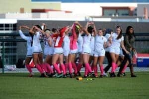 Girls soccer team celebrating on the field at Albuquerque Academy campus.