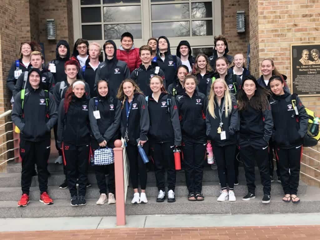 Group of students in athletic uniforms outside Albuquerque Academy campus.