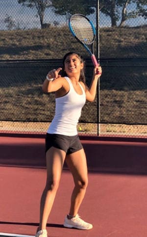 Young female tennis player performing serve on Albuquerque Academy sports court.