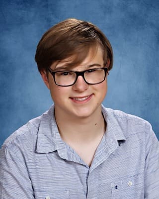 Young male student smiling at Albuquerque Academy graduation photo.