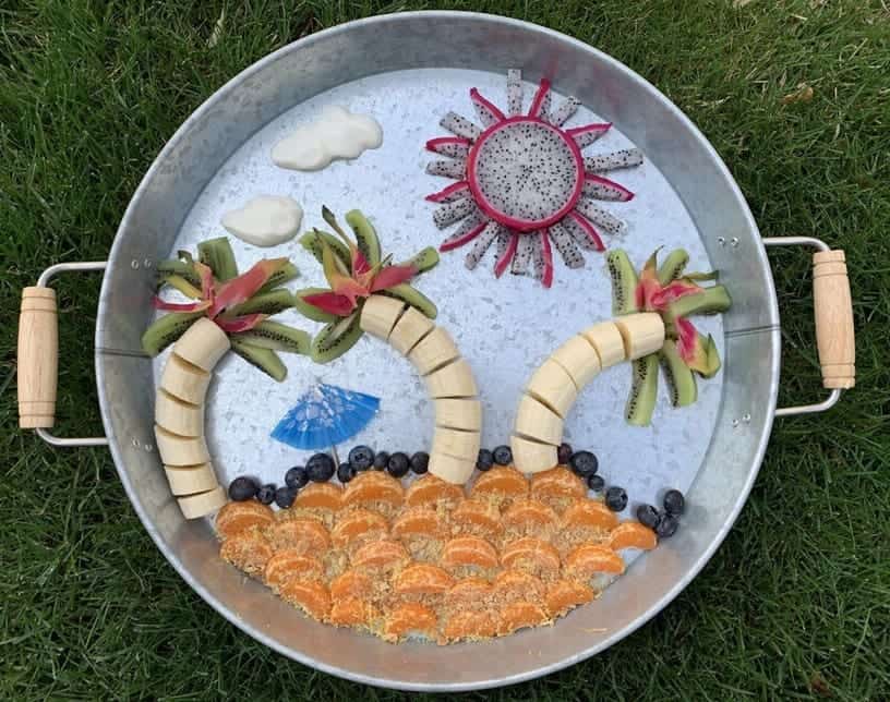 Vibrant fruit art display with watermelon, kiwi, blueberries, and oranges on a tray.