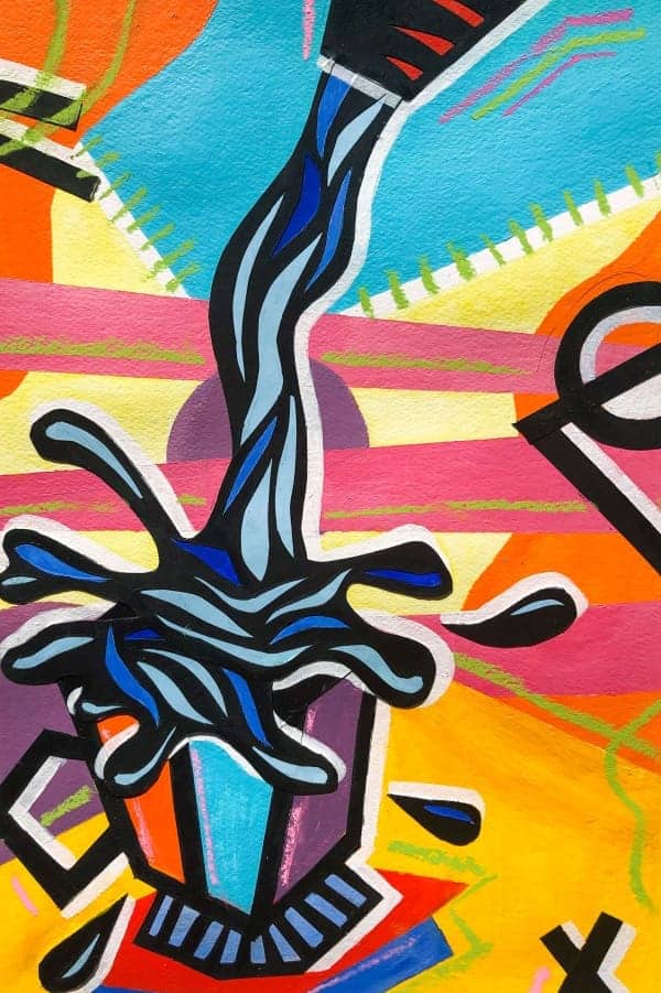 Colorful mural artwork of a paintbrush with ink splash, vibrant colors, Albuquerque Academy campus, creative arts education.
