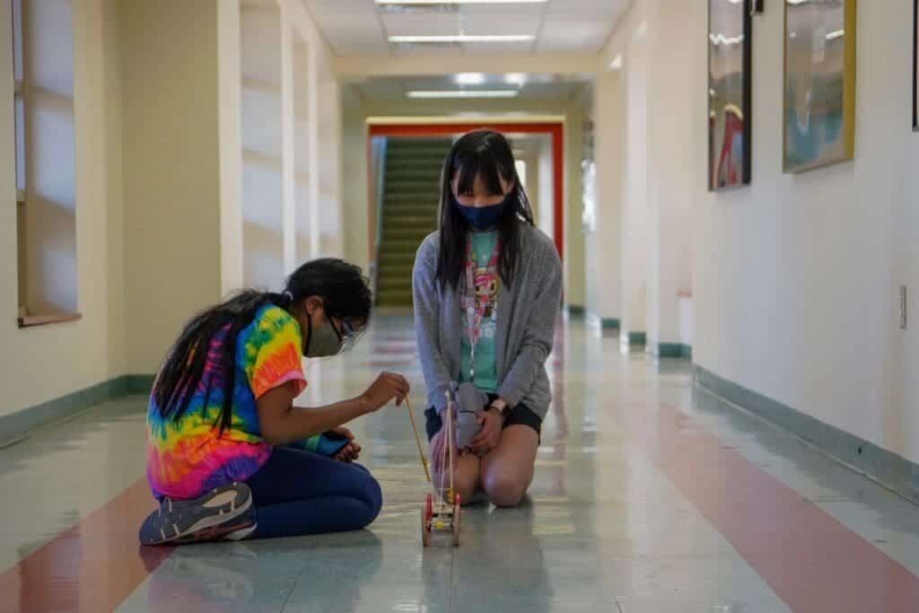 Brightly dressed students engaging with a science project in an Albuquerque Academy hallway.