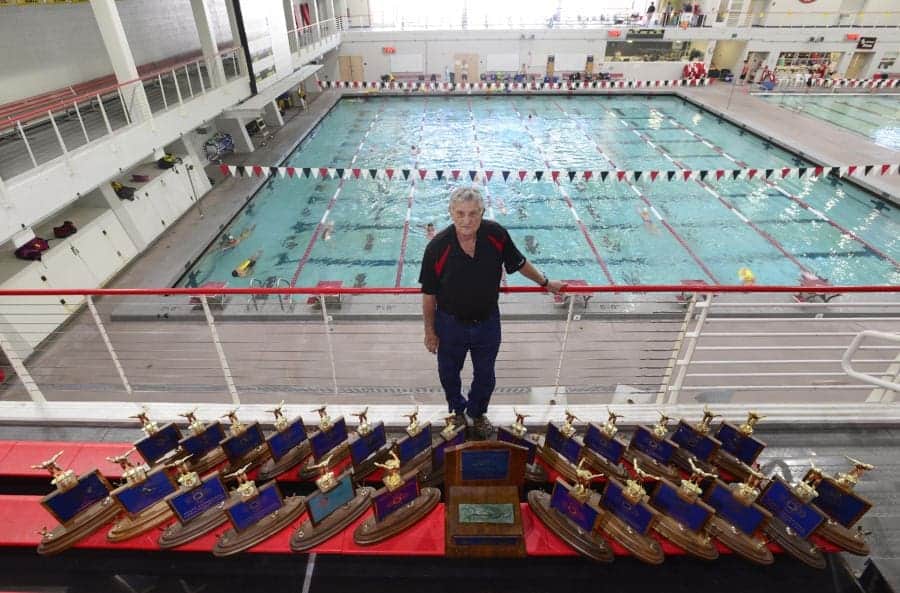 Bright indoor swimming pool at Albuquerque Academy with trophies and a coach in the foreground.