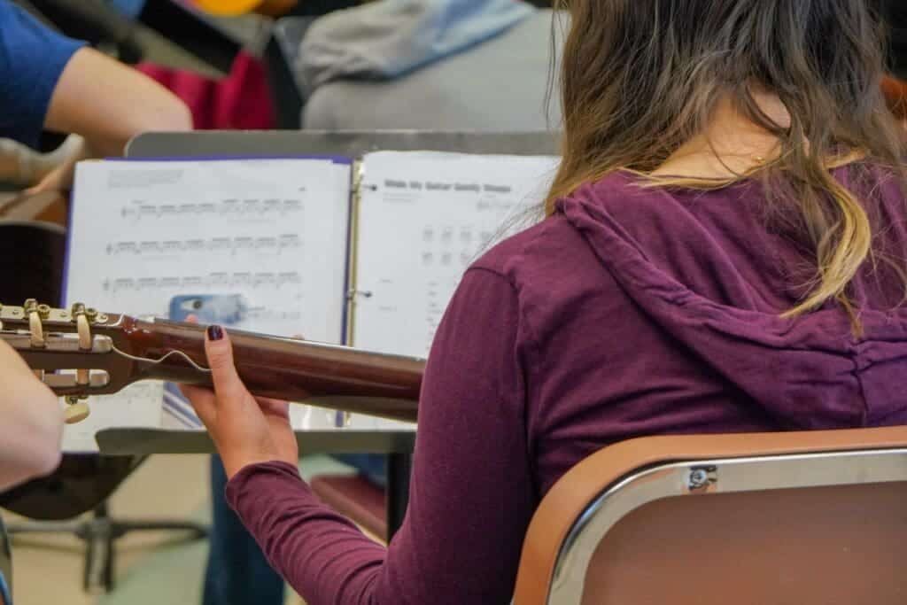 Music student playing guitar in Albuquerque Academy classroom.