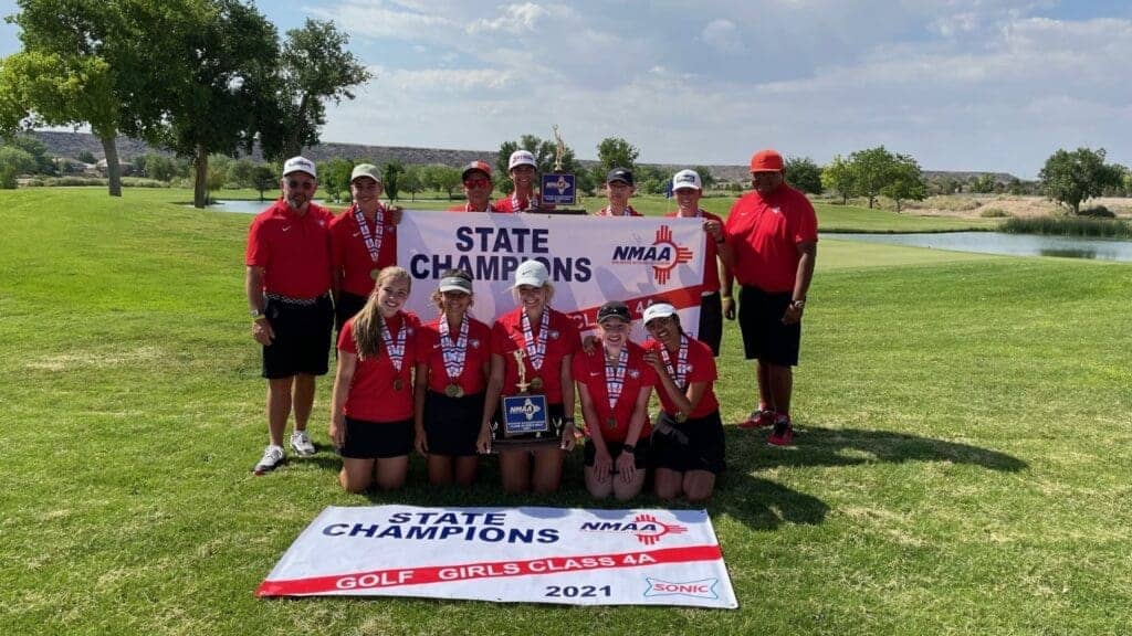 Championship golf team holding a banner on course, Albuquerque Academy sports victory.