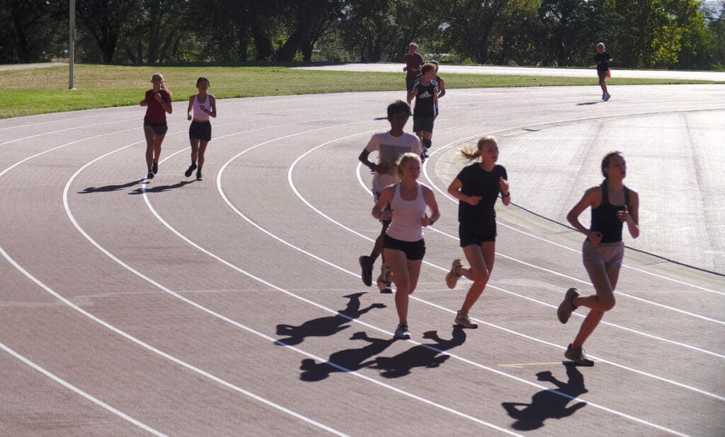 Bright students running on a track at Albuquerque Academy campus for sports and physical education.