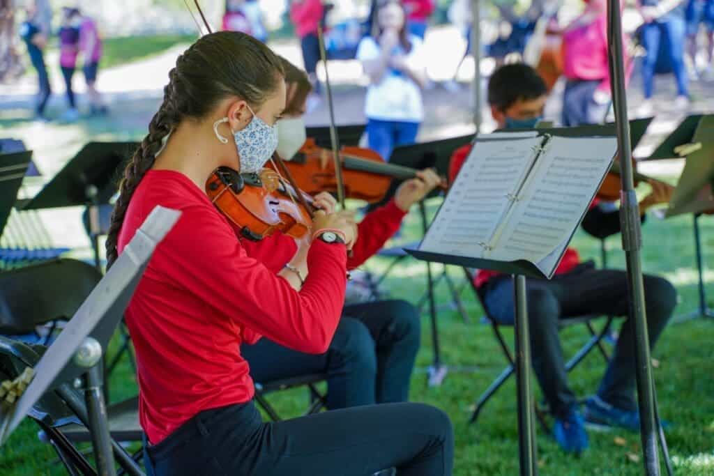 Young girl playing violin outdoors at Albuquerque Academy music event.
