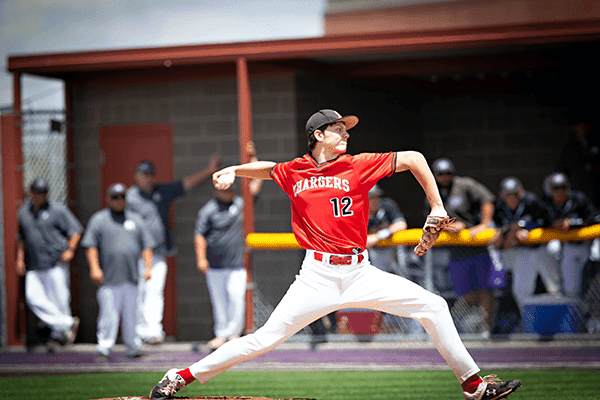 Youth baseball player pitching at Albuquerque Academy sports field.