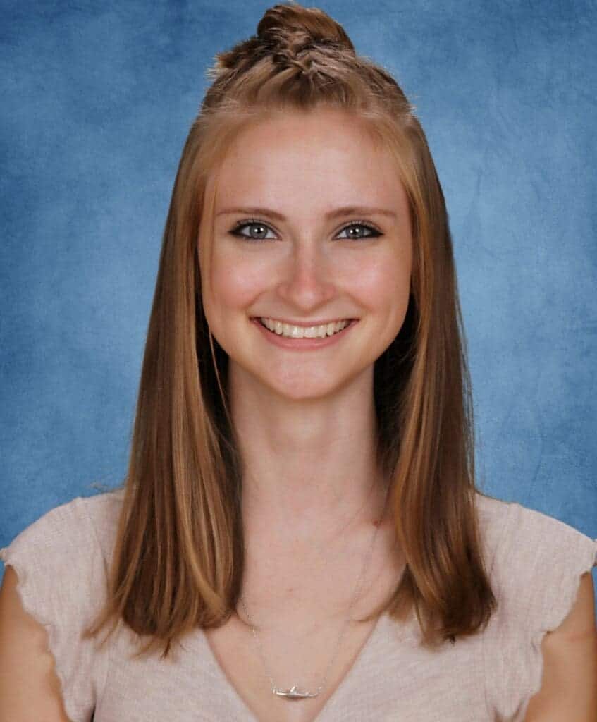 Smiling student portrait at Albuquerque Academy with a blue background.