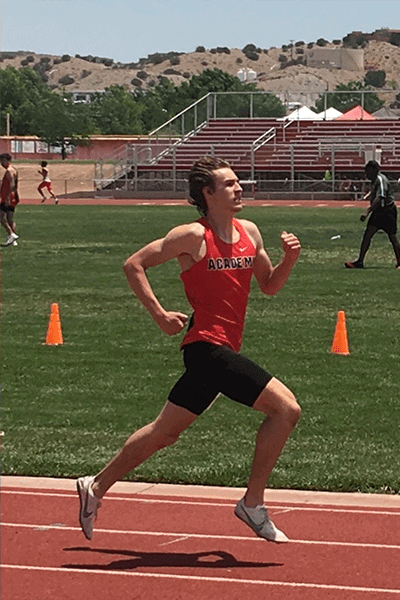 Albuquerque Academy student running on track during athletics event in New Mexico.