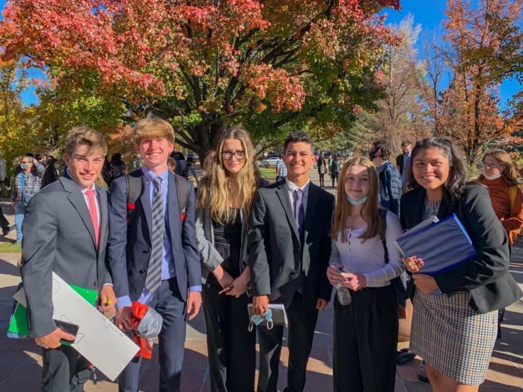 Diverse students in formal attire at Albuquerque Academy campus during fall season.