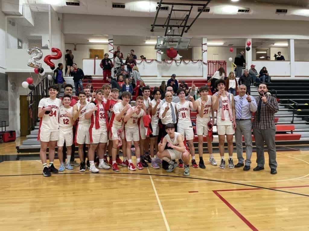 Basketball team celebrating victory at Albuquerque Academy gymnasium.
