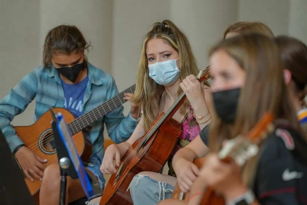 Students playing guitars and cello during school music class at Albuquerque Academy, New Mexico.