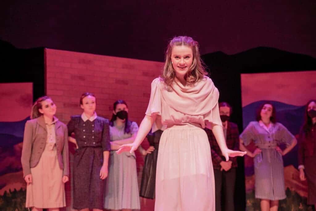 Vibrant theater production at Albuquerque Academy featuring students in period costumes on stage.