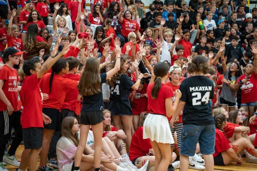 Engaged students at Albuquerque Academy sports event, diverse youth at school assembly, school community gathering, educational environment and student participation.