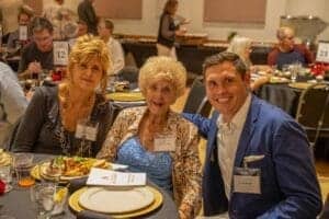 Albuquerque Academy alumni gathering at formal event, smiling with food and drinks.