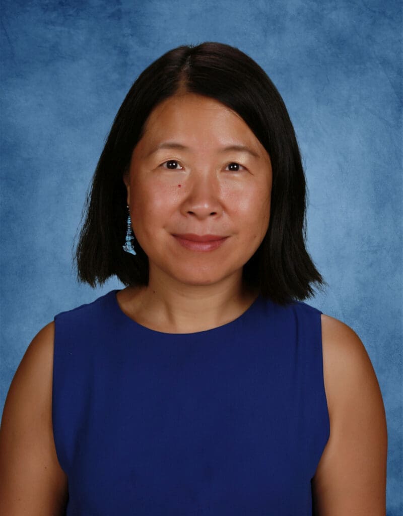 Diverse female student at Albuquerque Academy in front of blue background.