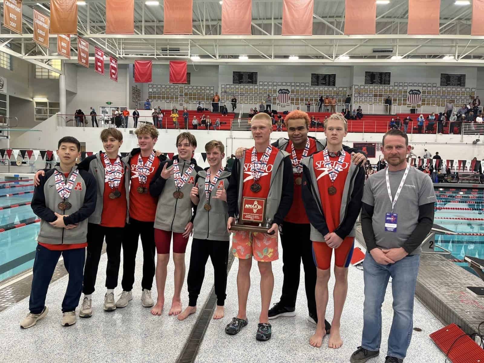 Medal-winning swim team at Albuquerque Academy's competitive swimming event in an indoor pool.