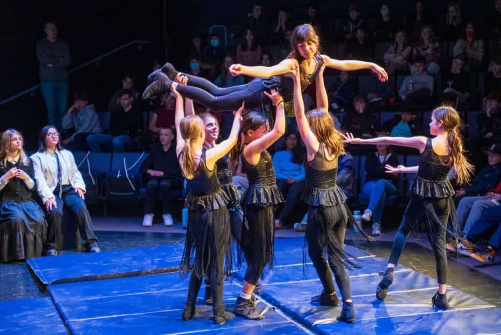 Young girls performing a dance routine on stage in front of an audience at Albuquerque Academy.