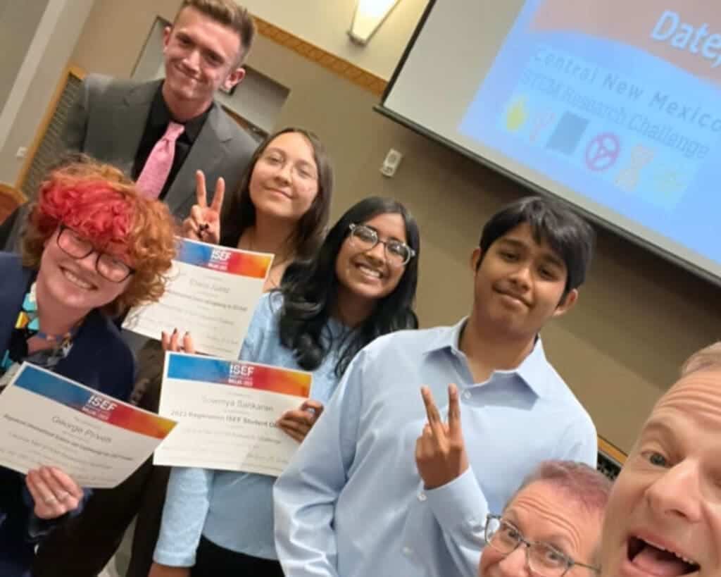 Diverse students celebrating with certificates at Albuquerque Academy graduation event.