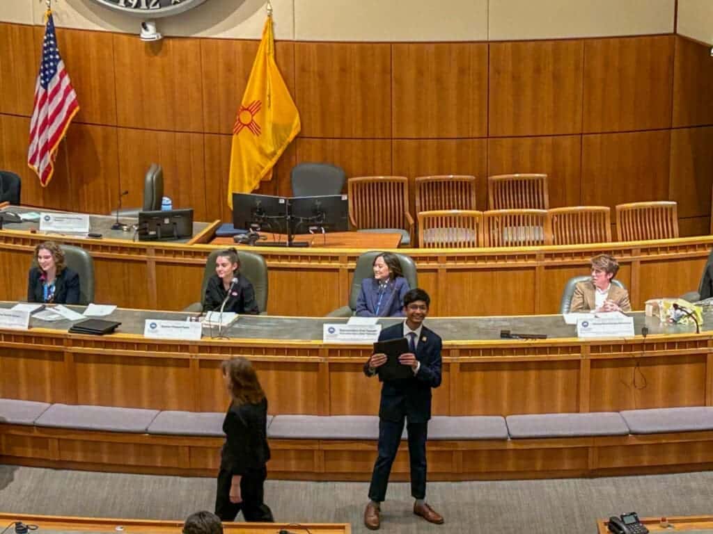 Diverse students participating in a debate in a wood-paneled auditorium at Albuquerque Academy.
