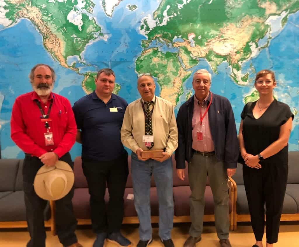 Diverse group of educators standing in front of a world map at Albuquerque Academy conference.