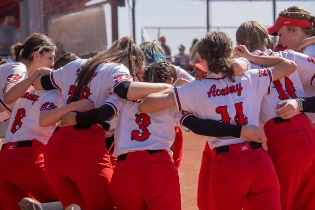 Girls high school softball team huddle on the field at Albuquerque Academy.