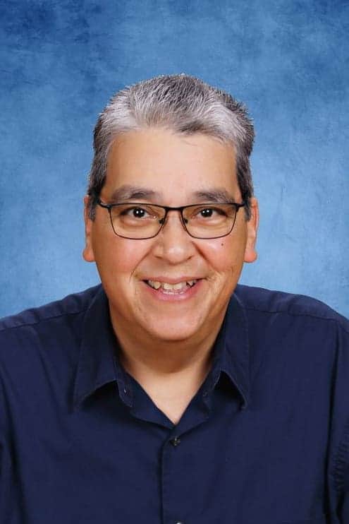 Experienced Albuquerque Academy faculty member smiling in classroom portrait.