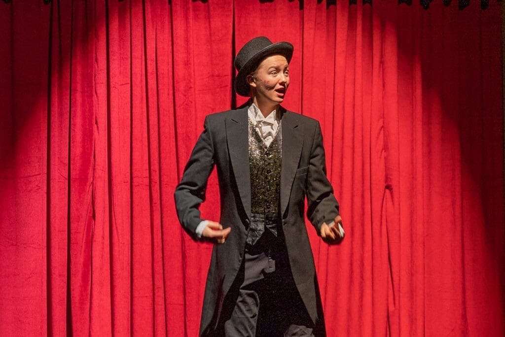 Famous actress performing on stage with red curtain background.
