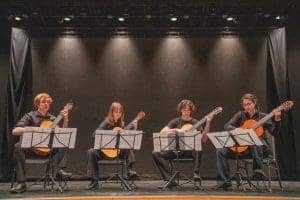 Students playing classical guitars on stage at Albuquerque Academy.