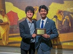 Smiling students in formal attire holding award at Albuquerque Academy event.
