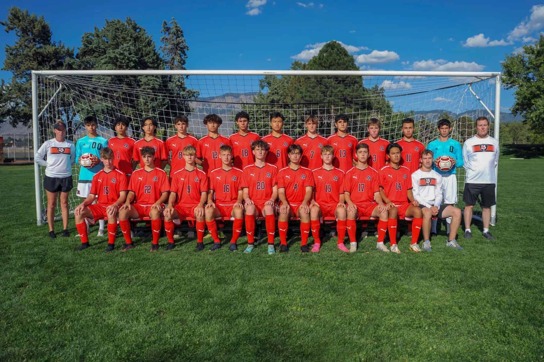 Albuquerque Academy soccer team posing for a group photo on the field with coaches and mountain backdrop.