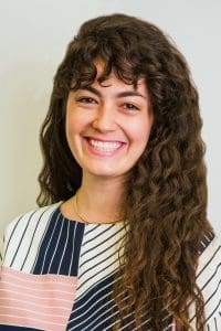 Smiling woman with curly hair and striped shirt.