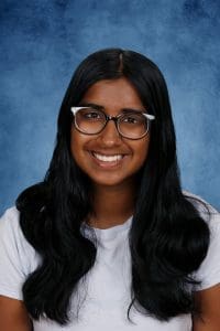 Smiling young woman with glasses on blue background.