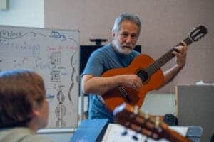 Guitar instructor teaching chords in music class.