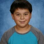 Boy smiling in blue and gray shirt