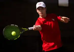 Tennis player swinging racket at approaching ball.