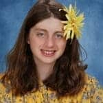Smiling girl with yellow flower hair accessory.