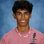 Bright portrait of diverse student with glasses smiling against blue background.