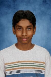Teen boy in striped shirt on blue background.