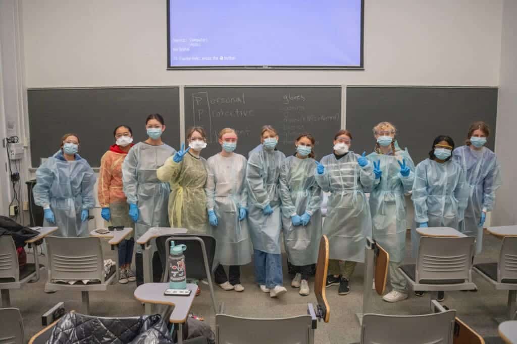 Albuquerque Academy students in science class, wearing masks and protective gowns for a hands-on experiment.