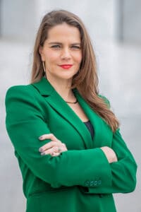 Professional woman in green blazer posing confidently.