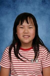 Girl smiling in red striped shirt.