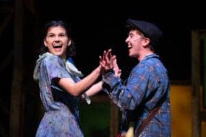 Two actors joyfully performing on stage.