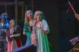 Actresses on stage in a dramatic theater performance.