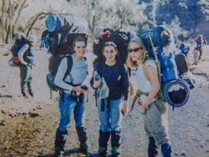 Three hikers with backpacks on trail.