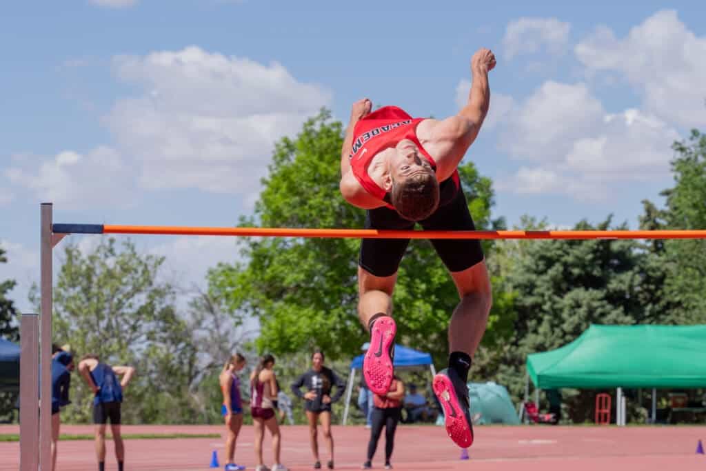 High school athlete clearing high jump bar during track and field competition at Albuquerque Academy.