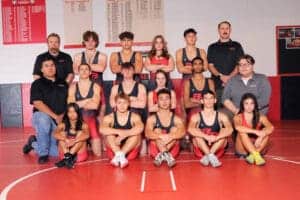 High school wrestling team posing in gym.