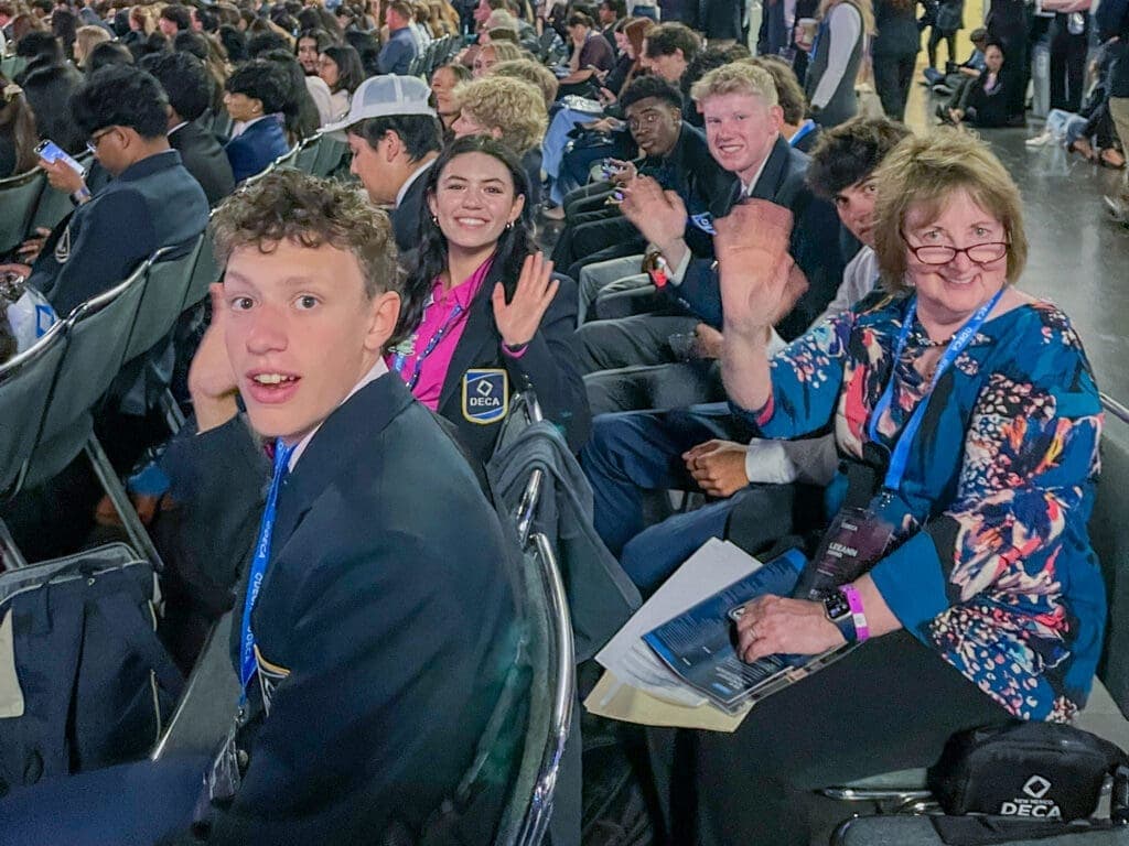 Students at Albuquerque Academy participating in a DECA conference, wearing badges and smiling.
